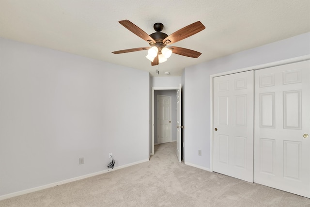 unfurnished bedroom with ceiling fan, light carpet, and a closet