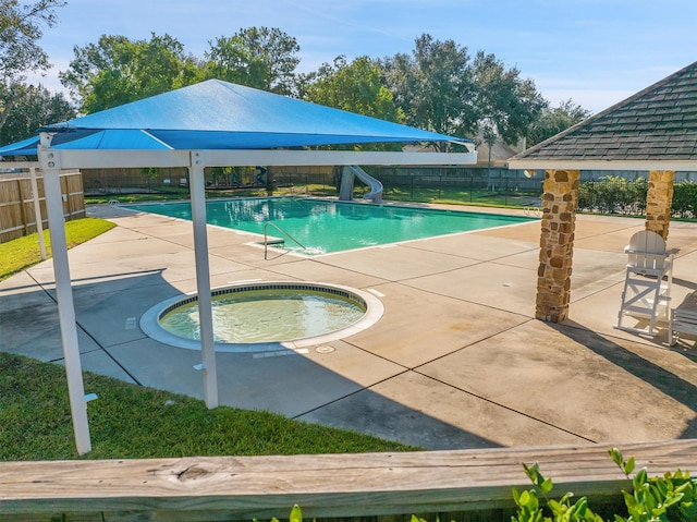 view of swimming pool featuring a patio, a hot tub, and a water slide