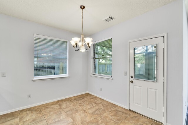 unfurnished dining area featuring a textured ceiling and a chandelier