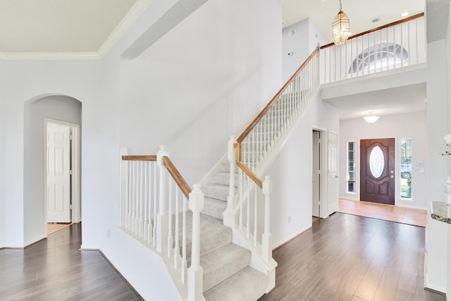 entrance foyer with crown molding, dark hardwood / wood-style flooring, and a towering ceiling