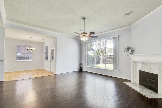 unfurnished living room with a tiled fireplace, ceiling fan with notable chandelier, wood-type flooring, and a textured ceiling