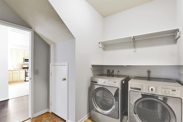 laundry room featuring washer and dryer, wood-type flooring, and a textured ceiling