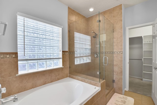 bathroom featuring tile patterned flooring, independent shower and bath, a textured ceiling, and a wealth of natural light