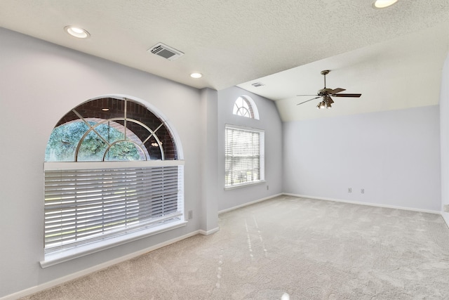 interior space featuring a textured ceiling, ceiling fan, lofted ceiling, and light carpet