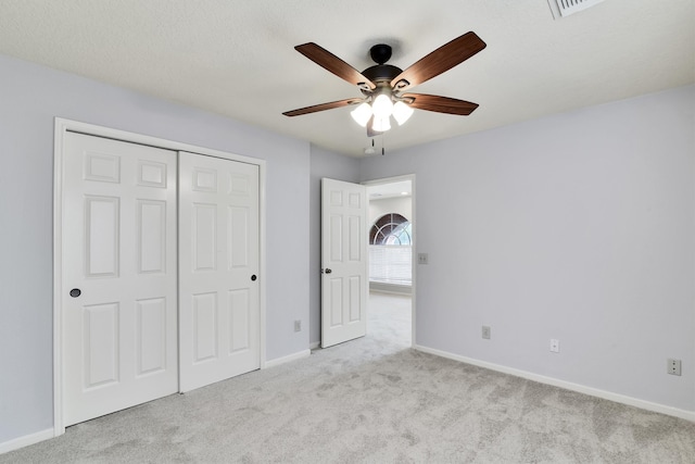 unfurnished bedroom with light carpet, a textured ceiling, a closet, and ceiling fan