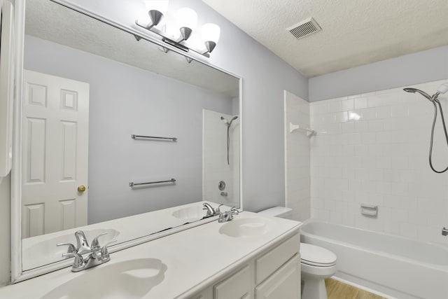 full bathroom featuring a textured ceiling, toilet, hardwood / wood-style flooring, vanity, and tiled shower / bath