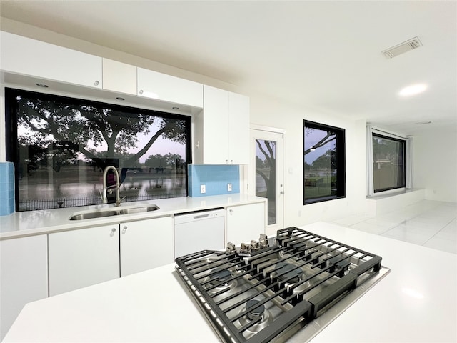 kitchen featuring gas cooktop, backsplash, sink, dishwasher, and white cabinetry