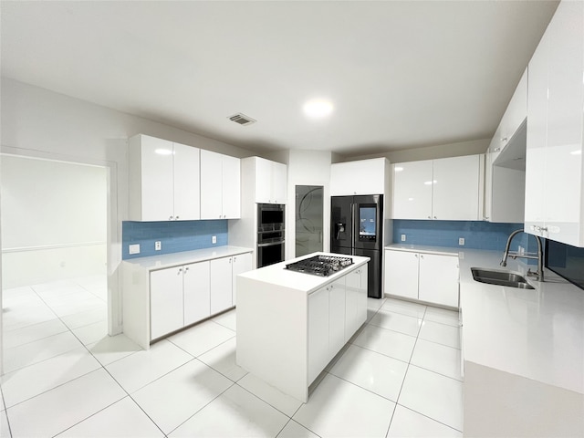 kitchen featuring white cabinets, sink, decorative backsplash, appliances with stainless steel finishes, and a kitchen island