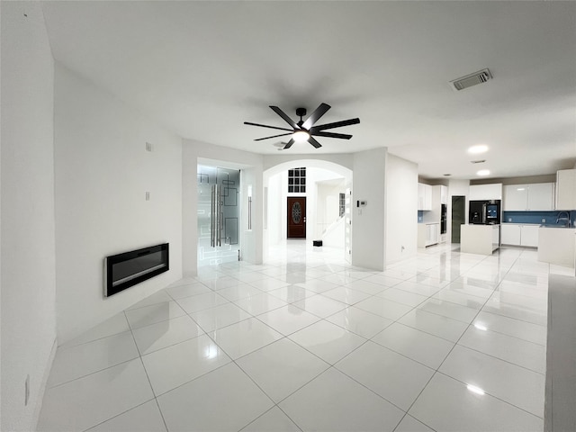 unfurnished living room featuring ceiling fan, light tile patterned floors, and sink