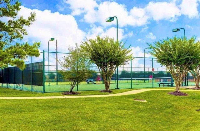 view of home's community with a lawn and tennis court