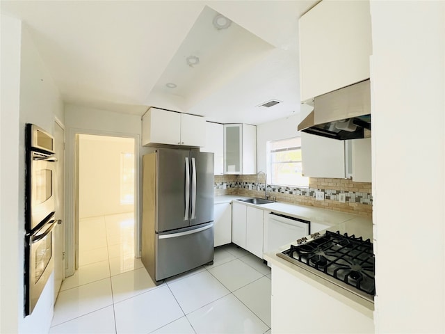 kitchen featuring backsplash, stainless steel appliances, sink, white cabinets, and light tile patterned flooring