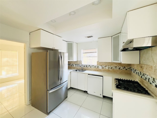 kitchen with white cabinetry, dishwasher, sink, stainless steel fridge, and decorative backsplash