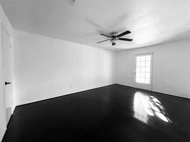 empty room with a textured ceiling, ceiling fan, and dark wood-type flooring