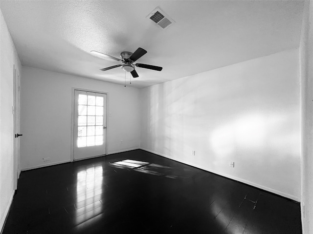 empty room with ceiling fan, wood-type flooring, and a textured ceiling