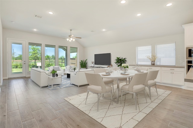 dining space with ceiling fan, lofted ceiling, and light hardwood / wood-style flooring