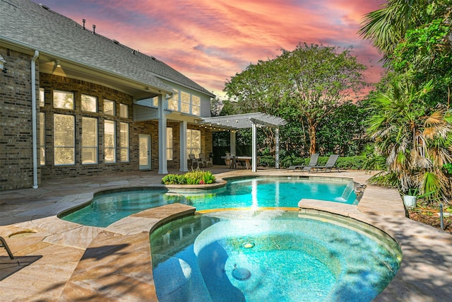 pool at dusk featuring an in ground hot tub, pool water feature, a patio area, and a pergola