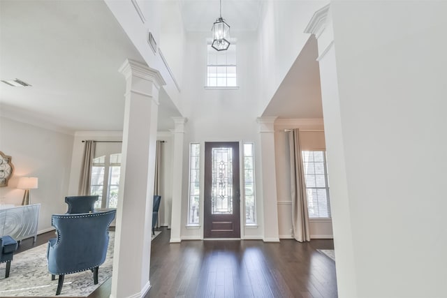 foyer featuring crown molding, a chandelier, dark hardwood / wood-style flooring, decorative columns, and a high ceiling