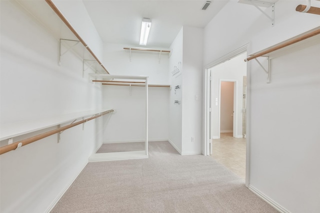 walk in closet with light carpet