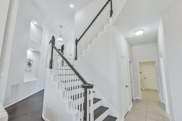 stairs with tile patterned flooring and a high ceiling