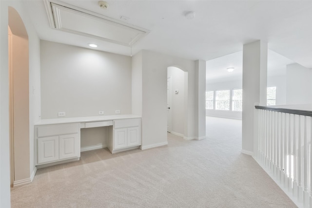 interior space featuring built in desk and light colored carpet