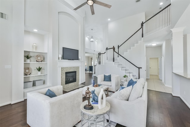 living room featuring dark wood-type flooring, built in features, a fireplace, and a towering ceiling