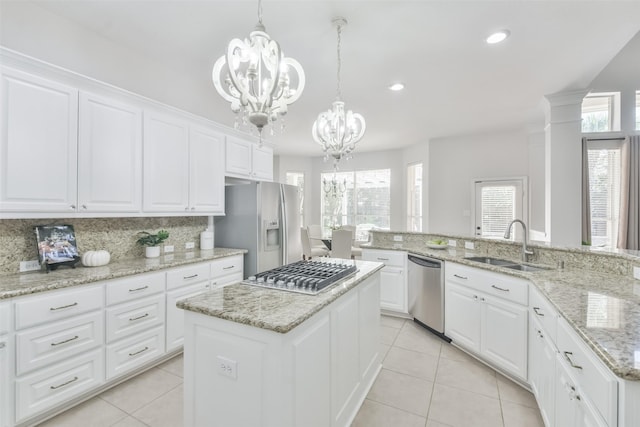 kitchen featuring sink, an inviting chandelier, stainless steel appliances, white cabinets, and a kitchen island