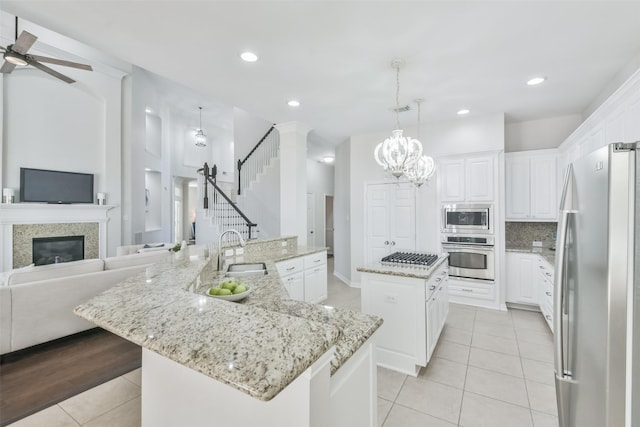 kitchen with sink, white cabinetry, pendant lighting, stainless steel appliances, and a kitchen island with sink