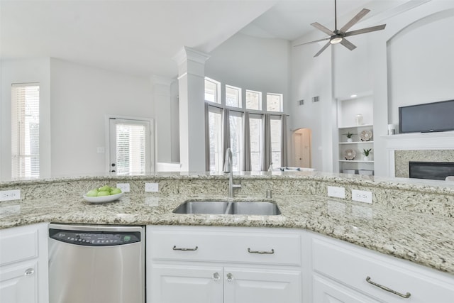 kitchen featuring light stone counters, stainless steel dishwasher, sink, and white cabinets