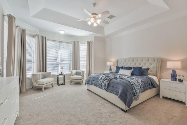 bedroom with light colored carpet, ceiling fan, and a tray ceiling