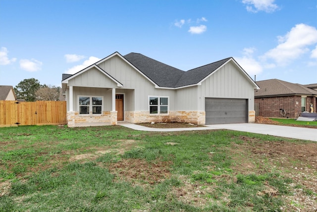 view of front facade with fence, concrete driveway, a front yard, a garage, and stone siding