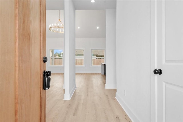 hallway featuring recessed lighting, light wood-type flooring, baseboards, and a notable chandelier