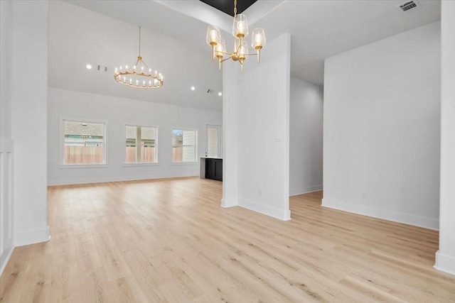 unfurnished living room featuring visible vents, baseboards, a notable chandelier, and light wood-style flooring