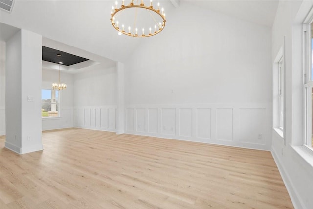 unfurnished room with light wood-type flooring, a decorative wall, an inviting chandelier, and visible vents