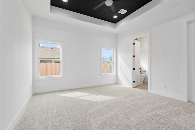 spare room with visible vents, a raised ceiling, carpet, and ceiling fan