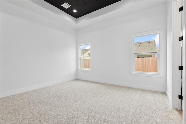 carpeted spare room with a raised ceiling, recessed lighting, visible vents, and baseboards