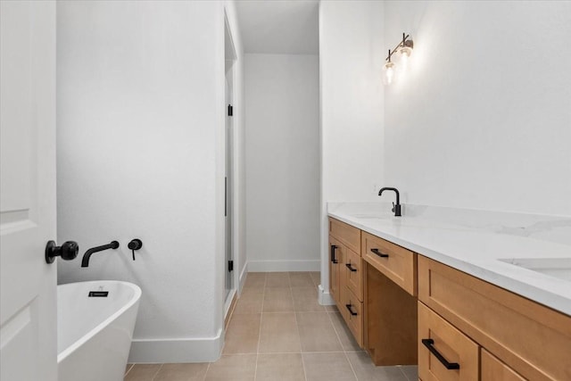 bathroom featuring tile patterned floors, a sink, double vanity, baseboards, and a soaking tub