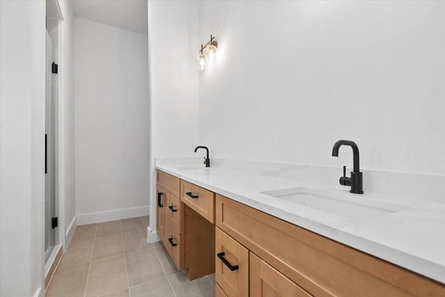 bathroom featuring tile patterned flooring, double vanity, baseboards, and a sink