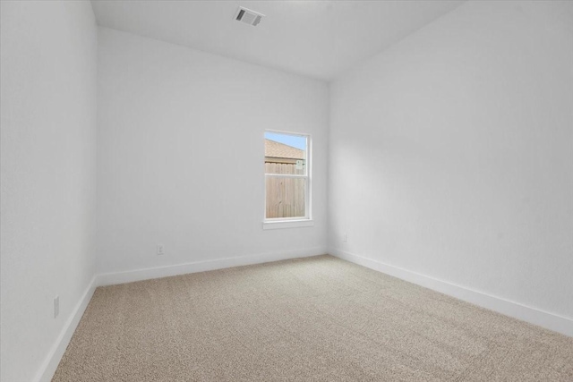 spare room with visible vents, baseboards, and light colored carpet