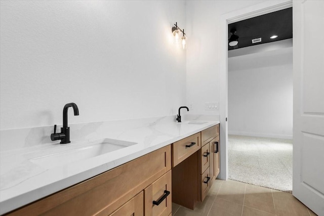 bathroom featuring a sink, baseboards, double vanity, and tile patterned floors