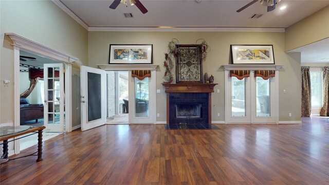 unfurnished living room with ceiling fan, french doors, dark hardwood / wood-style floors, crown molding, and a tiled fireplace