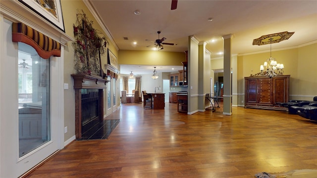 living room featuring crown molding, a fireplace, dark wood-type flooring, and ceiling fan with notable chandelier