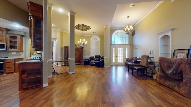 living room with crown molding, an inviting chandelier, dark wood-type flooring, and ornate columns