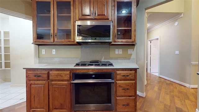 kitchen featuring light wood-type flooring, stainless steel appliances, and ornamental molding