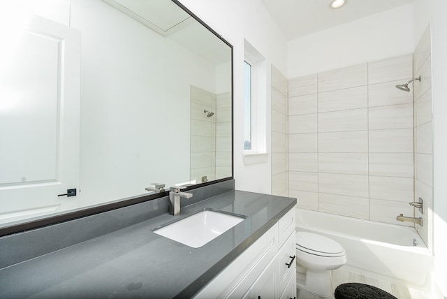 full bathroom featuring tiled shower / bath, vanity, and toilet