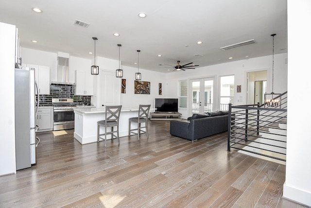 living room with ceiling fan with notable chandelier, light hardwood / wood-style floors, and french doors