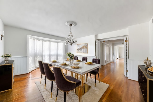 dining area with wood-type flooring and a notable chandelier