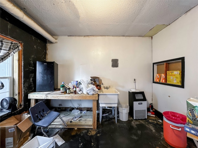 miscellaneous room with a textured ceiling, a workshop area, and concrete floors