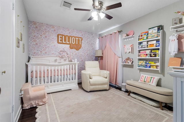 bedroom with ceiling fan, hardwood / wood-style floors, and a nursery area