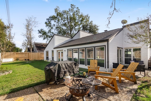 back of house featuring a lawn and an outdoor fire pit