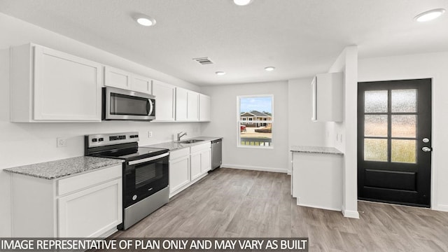 kitchen with sink, light hardwood / wood-style flooring, light stone counters, white cabinetry, and stainless steel appliances